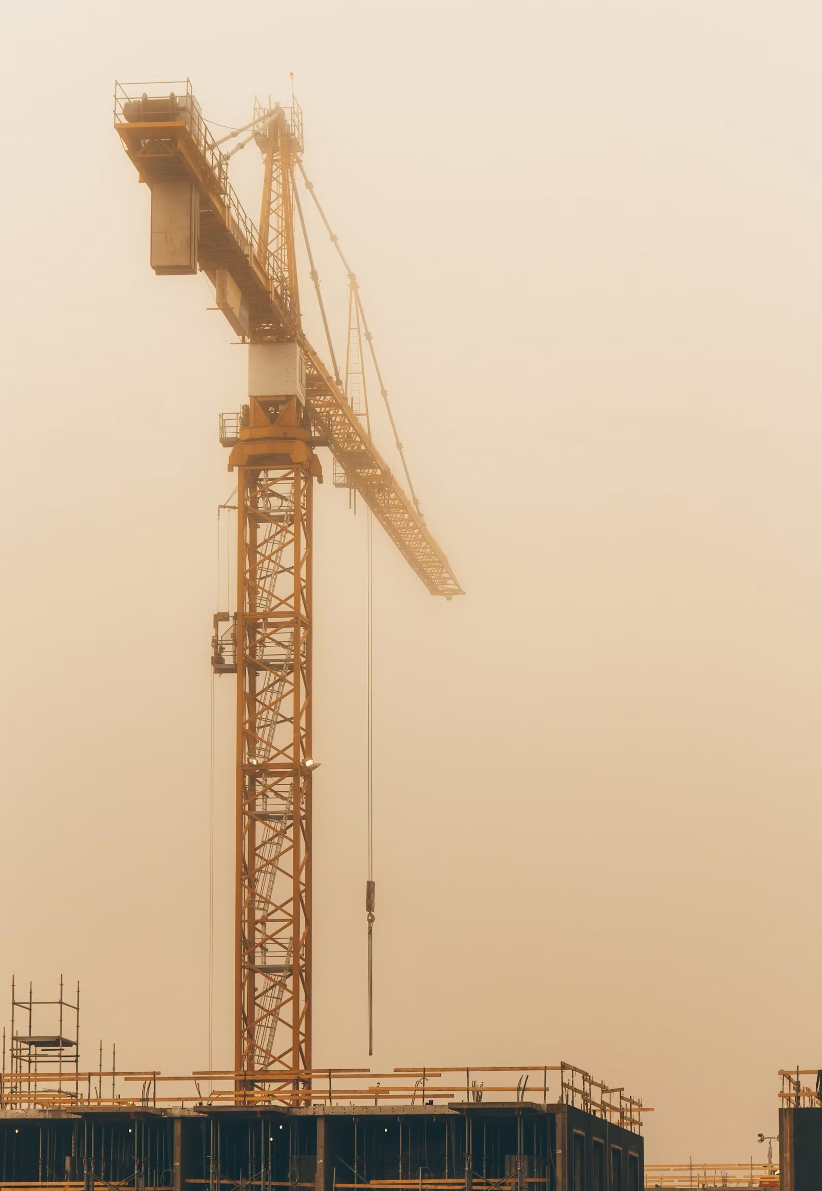 Yellow construction crane under grey sky